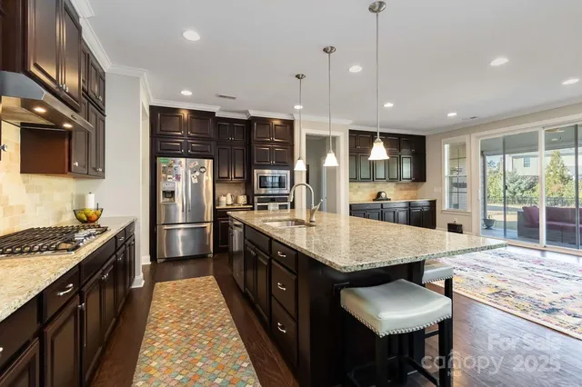 a open kitchen with stainless steel appliances granite countertop a stove top oven a refrigerator a sink and dishwasher