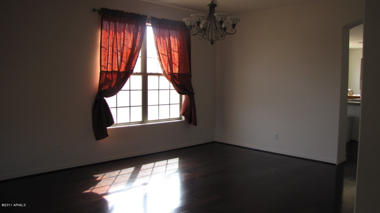 16007 West Pima Street Goodyear, AZ 85338 - Photo 5 of 35 an empty room with wooden floor and windows