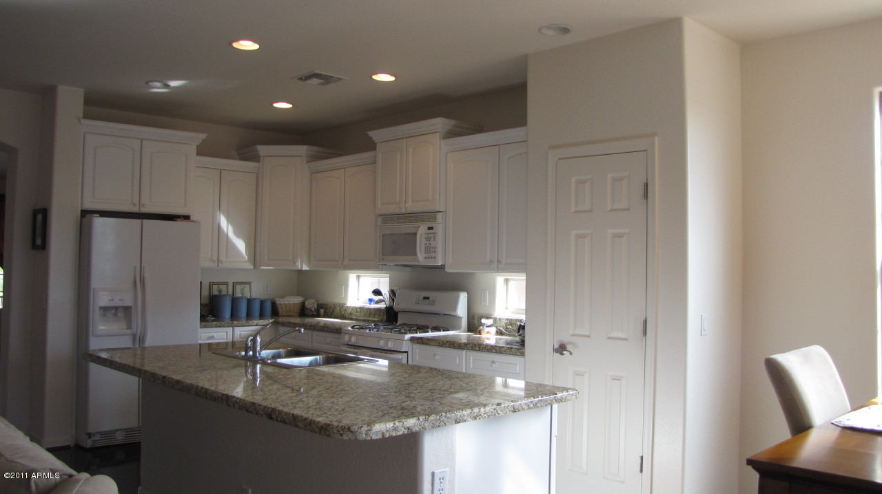 16007 West Pima Street Goodyear, AZ 85338 - Photo 9 of 35 a kitchen with stainless steel appliances granite countertop a sink a refrigerator and a granite counter tops