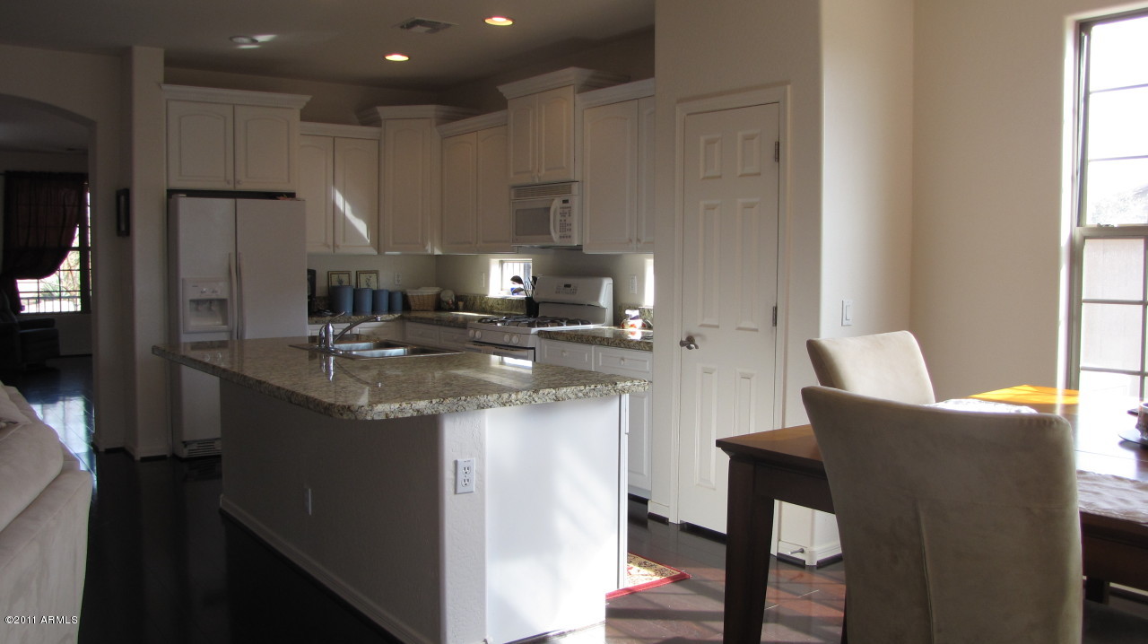 16007 West Pima Street Goodyear, AZ 85338 - Photo 10 of 35 a kitchen with kitchen island granite countertop a sink and refrigerator
