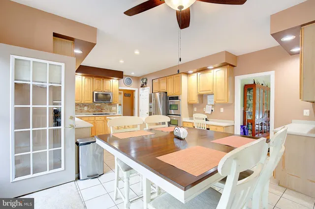 a dining hall with stainless steel appliances kitchen island granite countertop a table chairs and a view of living room