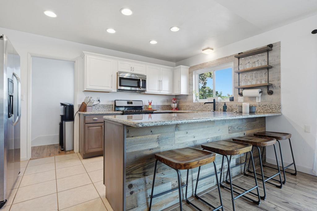 3328 Central Avenue Spring Valley, CA 91977 - Photo 6 of 54 a kitchen with kitchen island granite countertop a sink and a stove top oven with wooden floor
