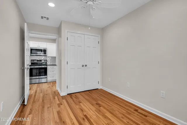 a view of a room with wooden floor and a ceiling fan