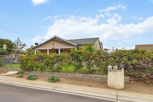 a front view of a house with a yard and potted plants