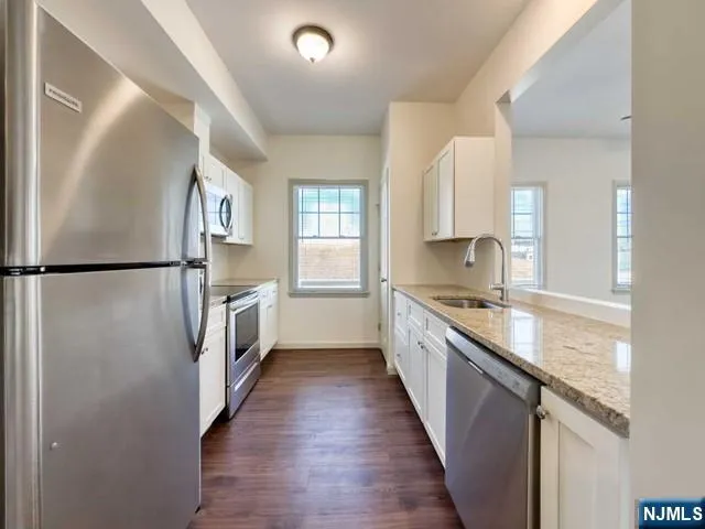 a kitchen with granite countertop a sink a counter space and stainless steel appliances