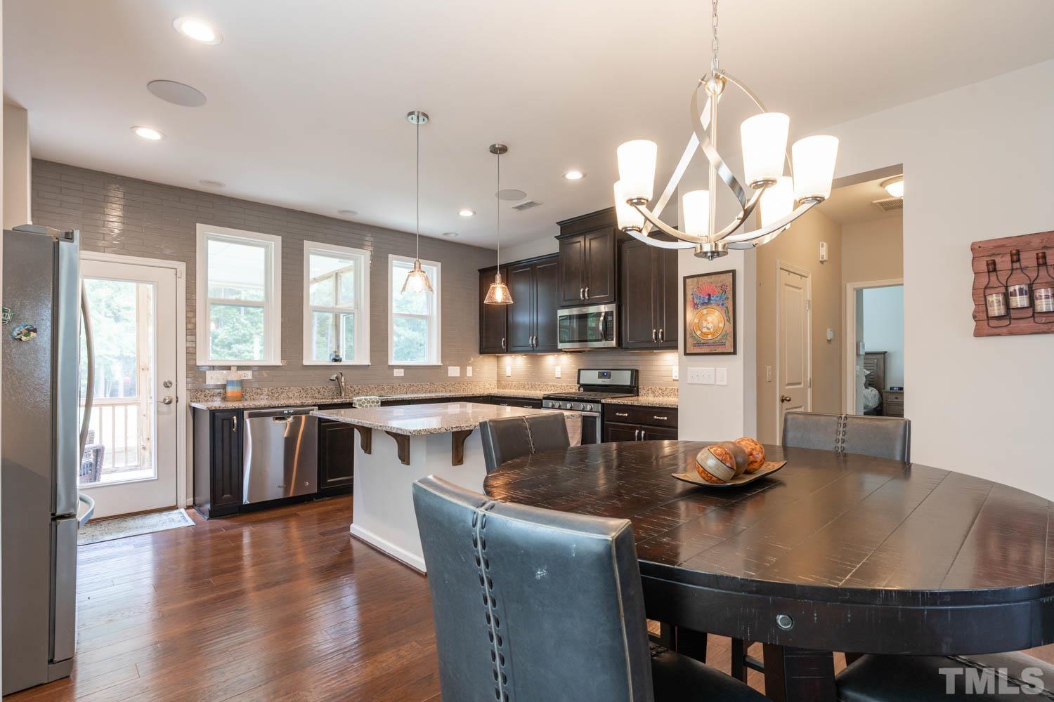 3565 Massey Ridge Court Raleigh, NC 27616 - Photo 9 of 22 a kitchen with stainless steel appliances granite countertop a stove a refrigerator a sink a dining table and chairs with wooden floor