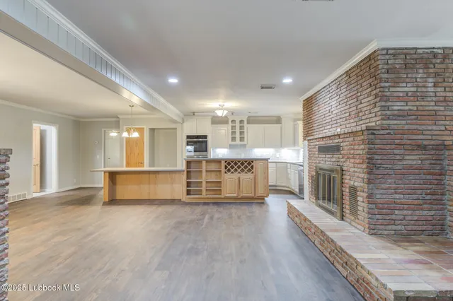 a view of kitchen with stainless steel appliances wooden floor and fireplace