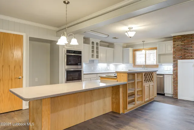 a large kitchen with stainless steel appliances a large counter top a sink and a stove