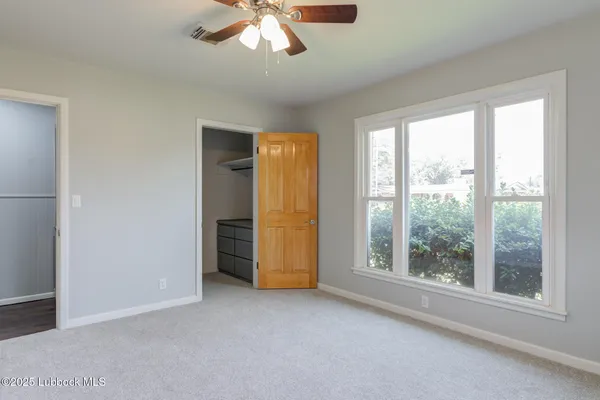 an empty room with windows and fan