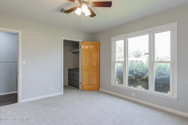an empty room with windows and fan