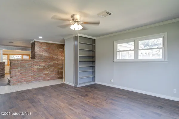 a view of an empty room with a window and wooden floor
