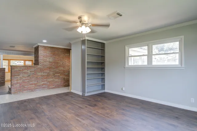 a view of an empty room with a window and wooden floor