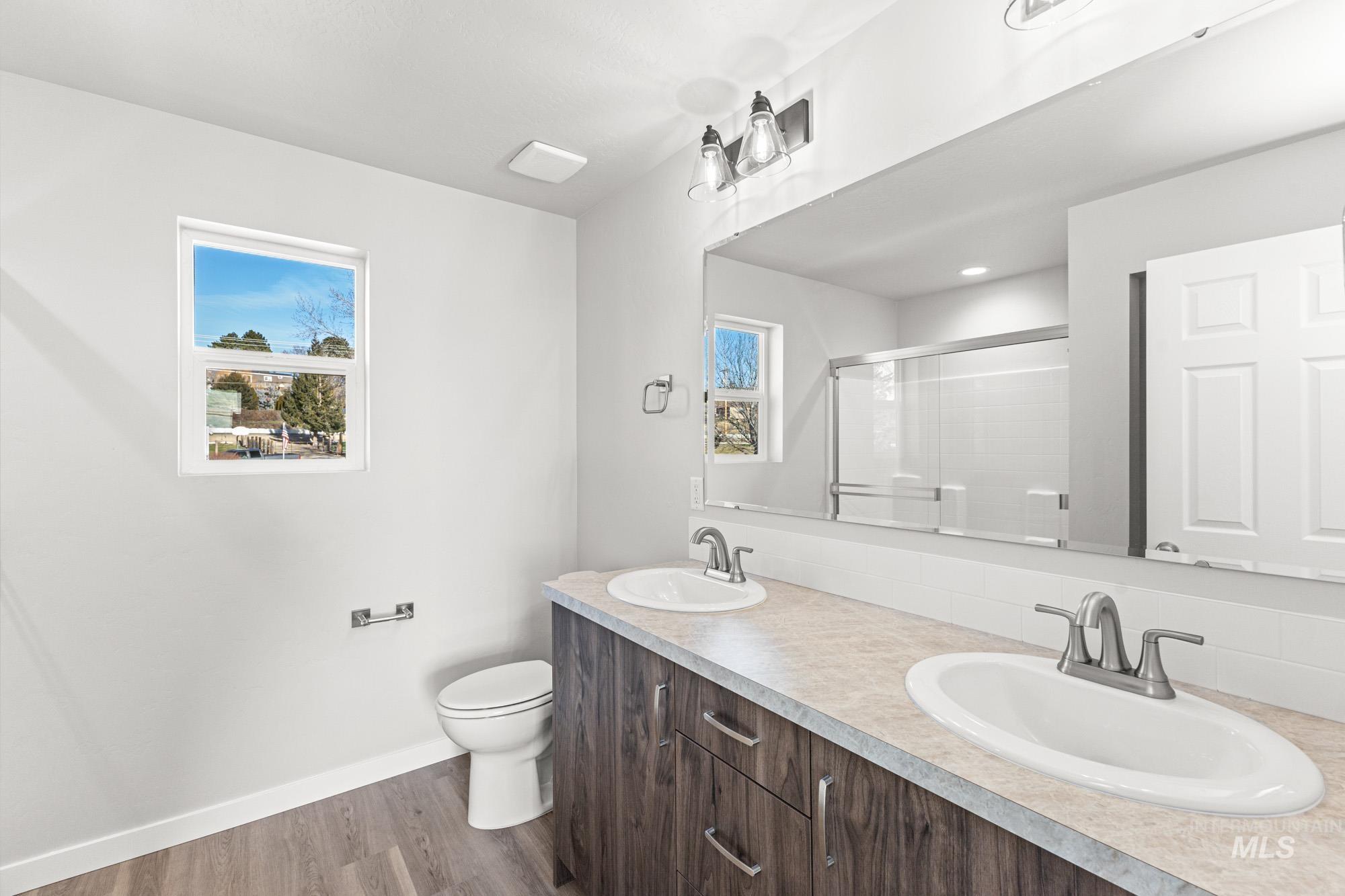 1436 Long Pond Street Middleton, ID 83644 - Photo 21 of 24 Bathroom featuring a shower stall, double vanity, dark wood finished floors, and healthy amount of natural light