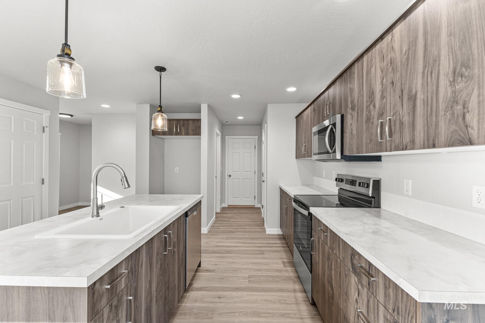 1436 Long Pond Street Middleton, ID 83644 - Photo 6 of 24 Kitchen with stainless steel appliances, modern cabinets, light countertops, decorative light fixtures, and a center island with sink