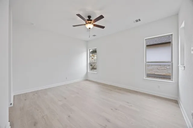 an empty room with a window and ceiling fan