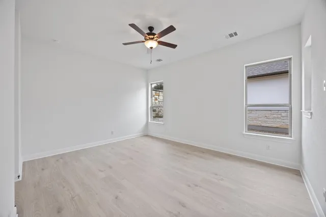 an empty room with a window and ceiling fan