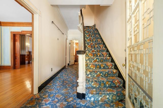 a view of an empty room with wooden floor fireplace and a window