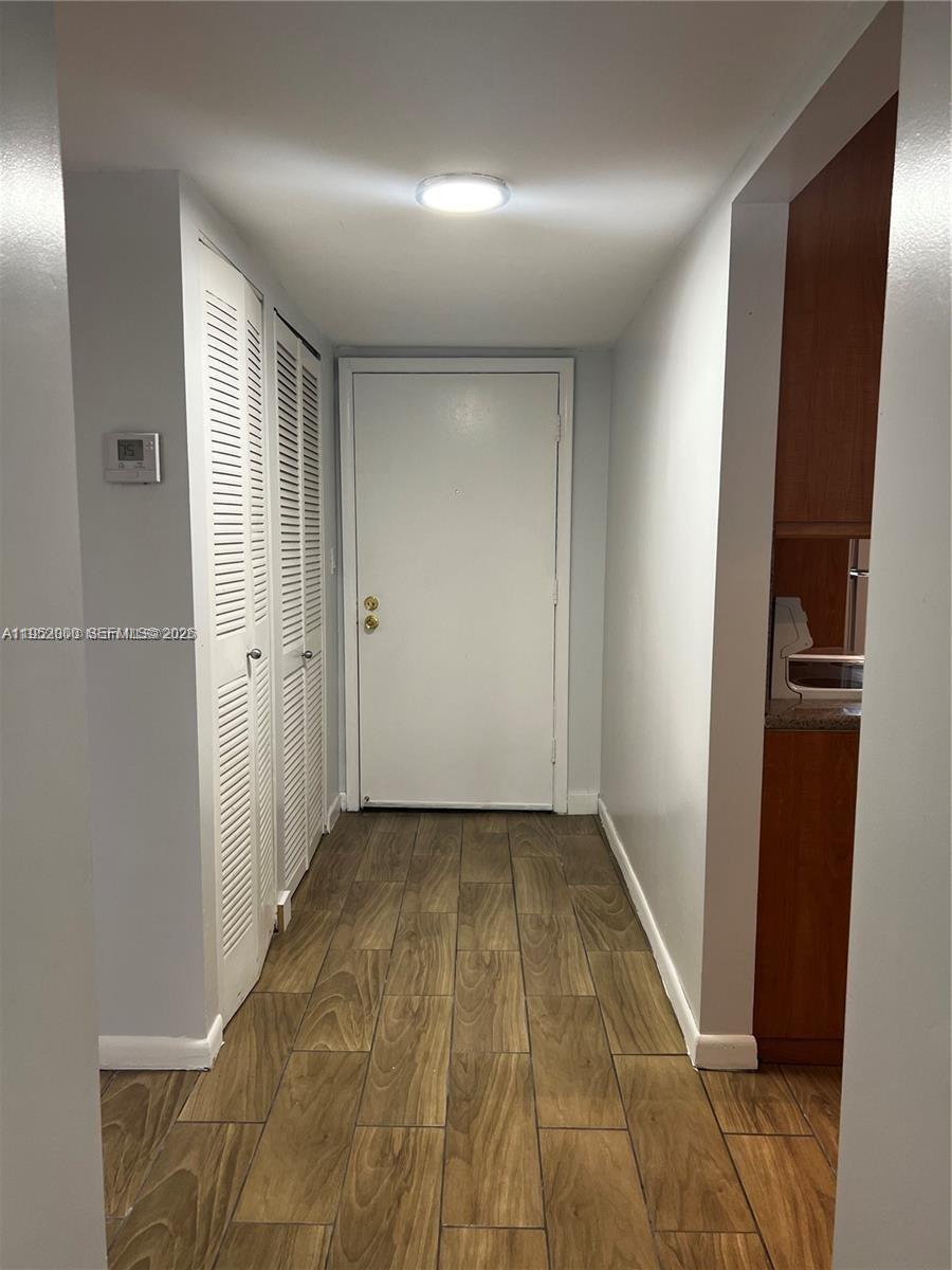4111 Stirling Road, Unit 308 Fort Lauderdale, FL 33314 - Photo 9 of 32 an empty room with wooden floor and a hallway