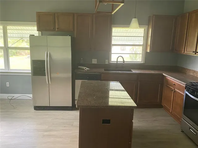 a kitchen with granite countertop a sink stove and refrigerator