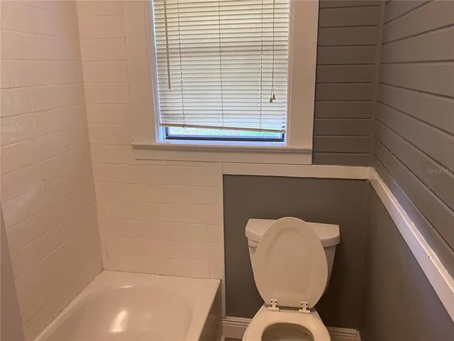 an empty room with wooden floor chandelier and windows