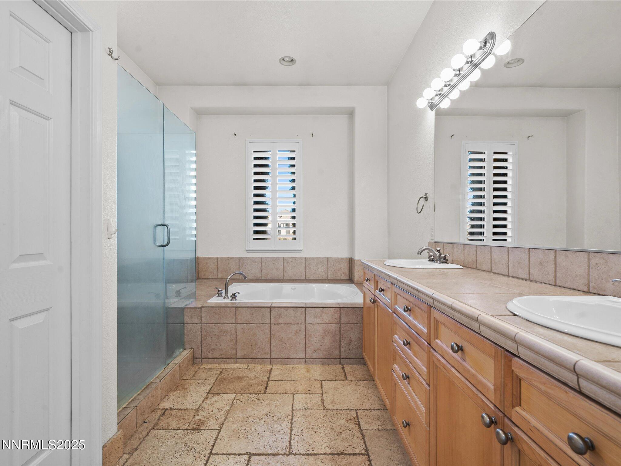 5519 New Mexico Court Reno, NV 89511 - Photo 27 of 60 a spacious bathroom with a granite countertop tub a double vanity sink a window and a mirror