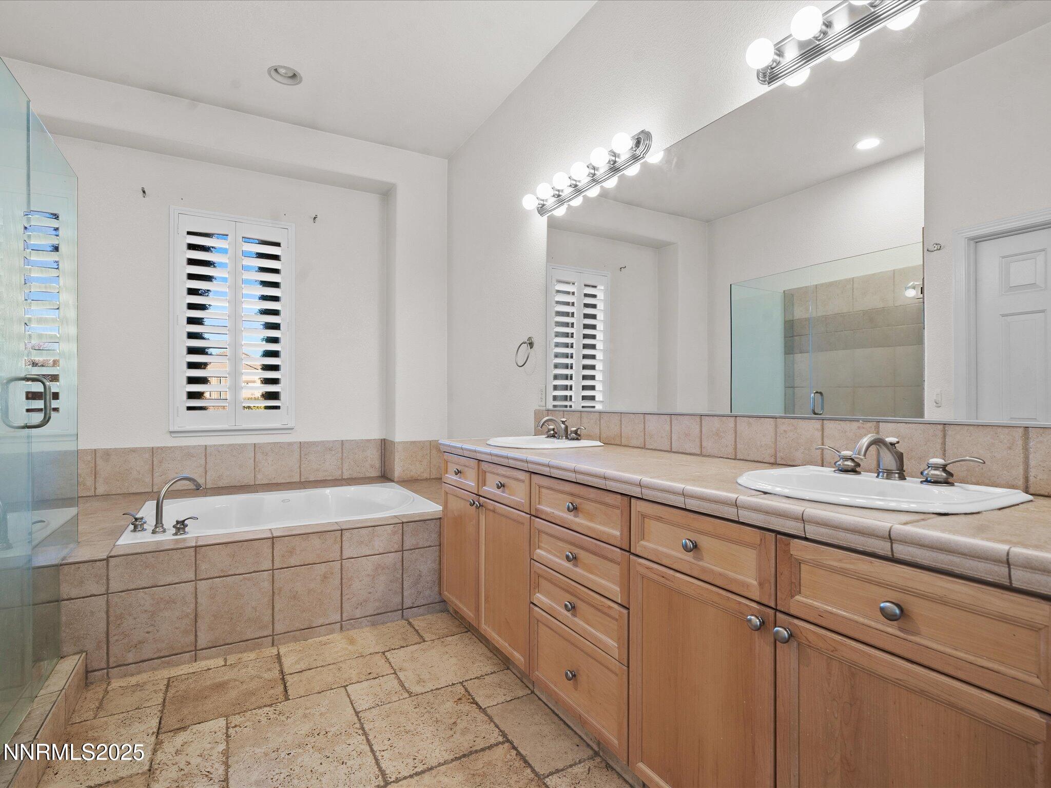 5519 New Mexico Court Reno, NV 89511 - Photo 28 of 60 a bathroom with a double vanity sink large mirror and a bathtub