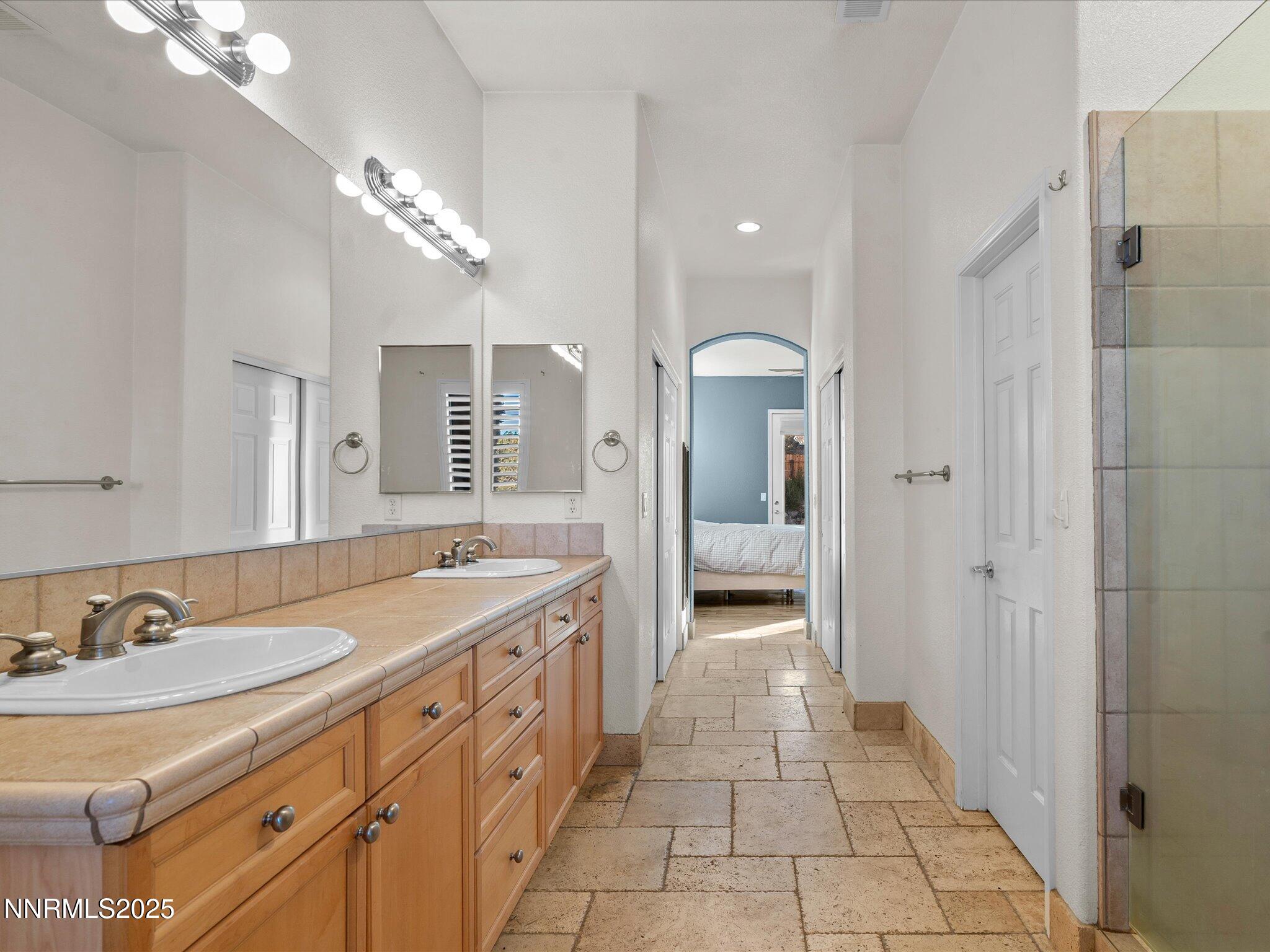 5519 New Mexico Court Reno, NV 89511 - Photo 31 of 60 a spacious bathroom with a granite countertop sink a mirror a vanity and shower