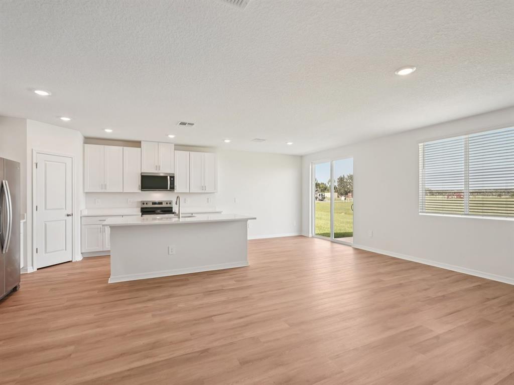 7722 Satterfield Terrace Parrish, FL 34219 - Photo 3 of 22 a view of kitchen with kitchen island granite countertop a stove top oven a sink and white cabinets with wooden floor