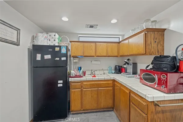 a living room with stainless steel appliances furniture a kitchen view and wooden floor