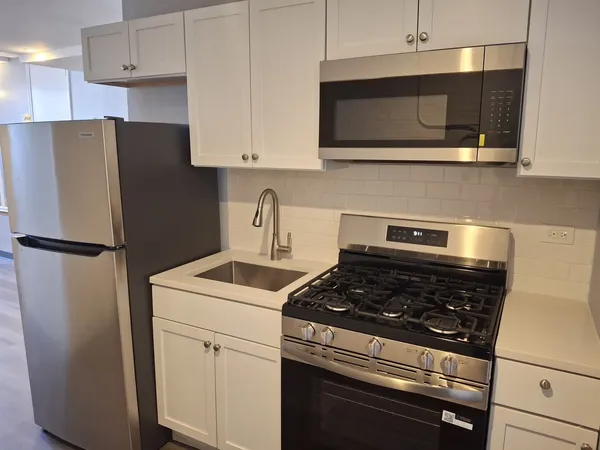 a kitchen with stainless steel appliances granite countertop white cabinets a refrigerator a stove a microwave oven and white cabinets