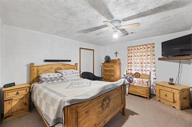 a bedroom with a bed and a flat tv screen on dresser