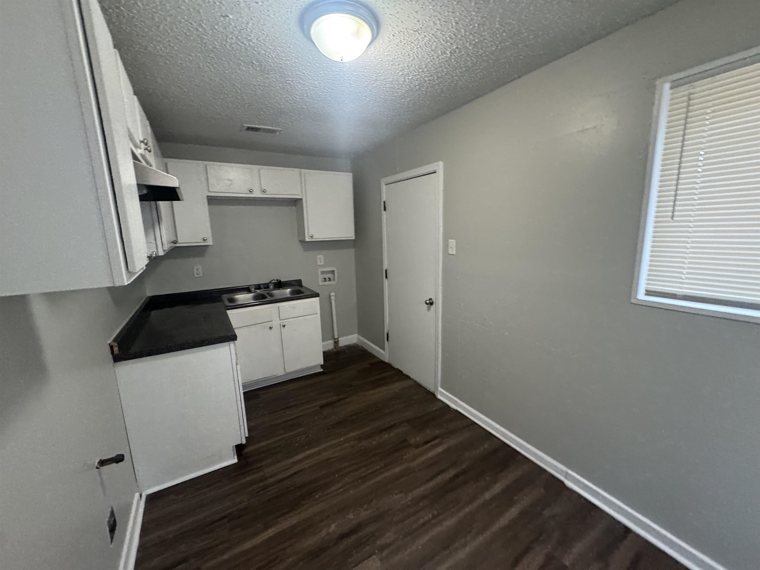 220 Elder Road Memphis, TN 38109 - Photo 5 of 9 Kitchen with white cabinetry, a textured ceiling, dark wood finished floors, and dark countertops