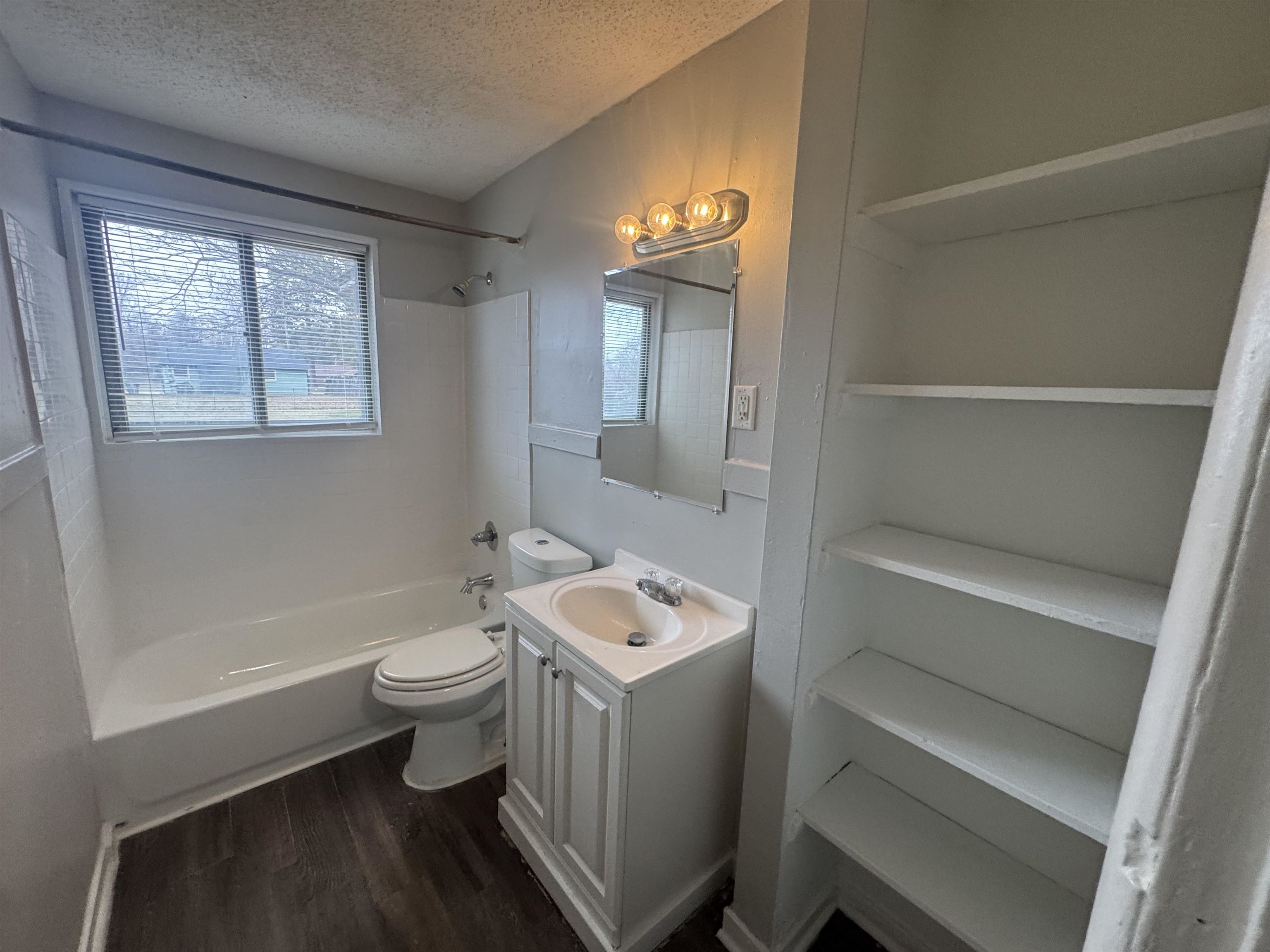 220 Elder Road Memphis, TN 38109 - Photo 9 of 9 Bathroom with a textured ceiling, dark wood-style flooring, shower / washtub combination, vanity, and healthy amount of natural light