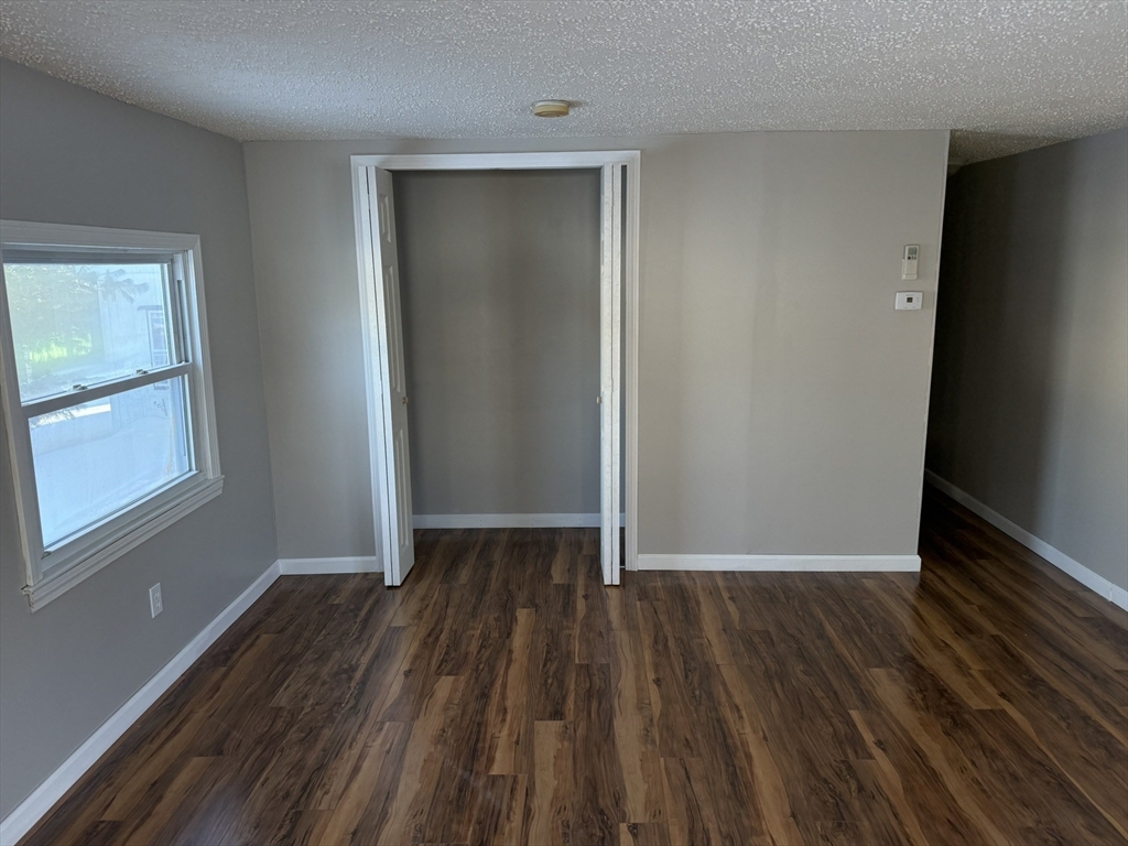 281 Chauncey Walker Street, Unit 188 Belchertown, MA 01007 - Photo 11 of 19 an empty room with wooden floor and windows