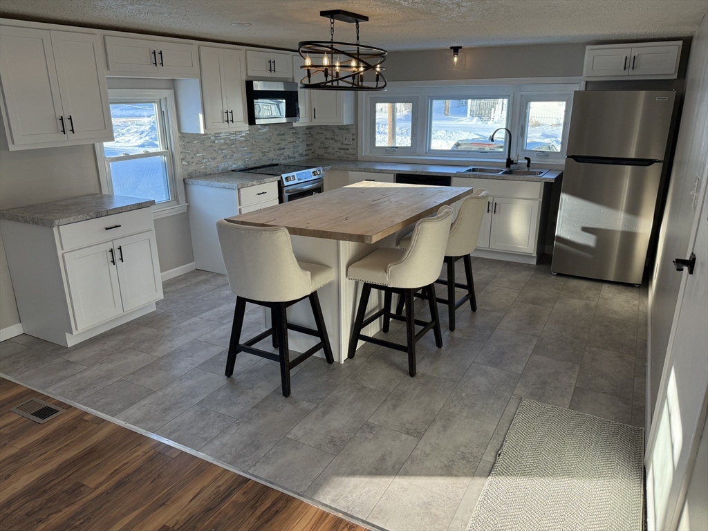 281 Chauncey Walker Street, Unit 188 Belchertown, MA 01007 - Photo 2 of 19 a kitchen with stainless steel appliances granite countertop a sink a stove a refrigerator a dining table and chairs