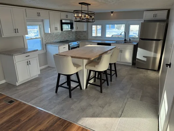 a kitchen with stainless steel appliances granite countertop a sink a stove a refrigerator a dining table and chairs