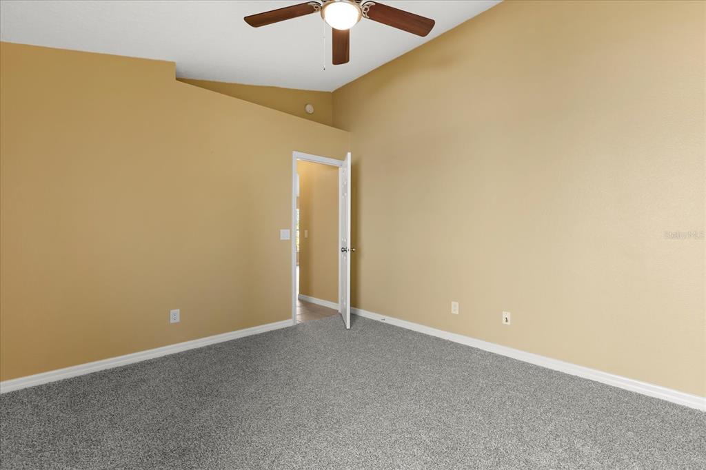 619 Rhodes Drive DeLand, FL 32720 - Photo 30 of 37 an empty room with a ceiling fan and carpet