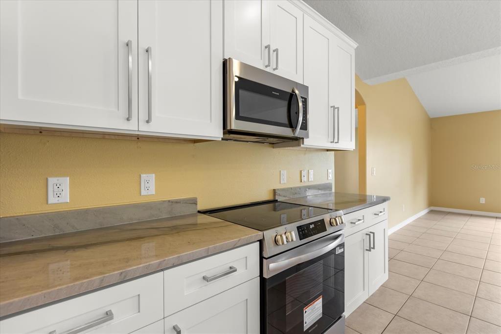 619 Rhodes Drive DeLand, FL 32720 - Photo 7 of 37 a kitchen with granite countertop white cabinets stainless steel appliances and a counter space