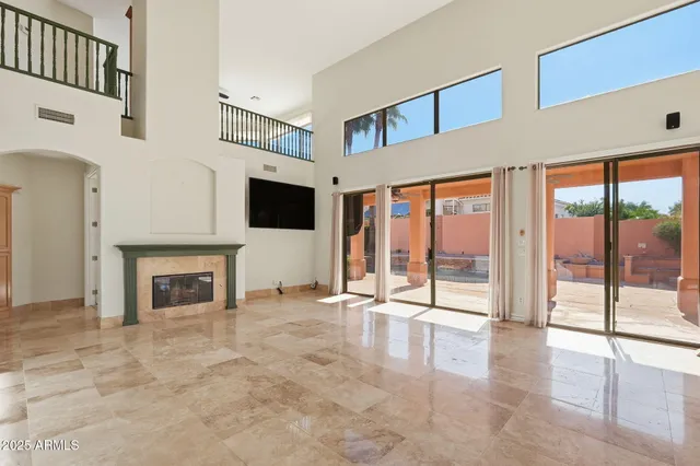 a view of an empty room with fireplace and windows