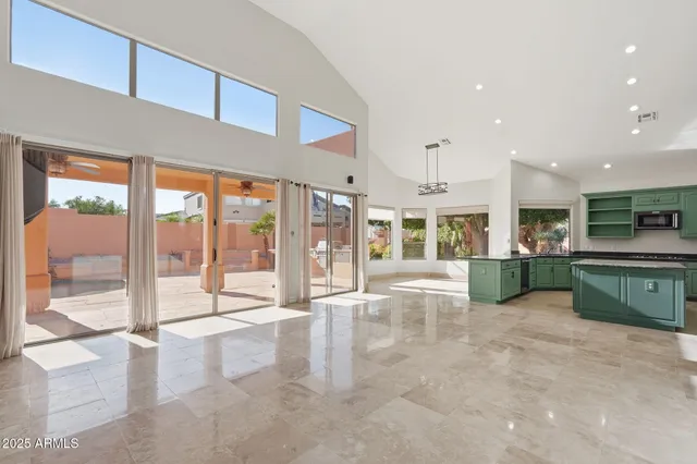 a view of an empty room with kitchen view and a large window