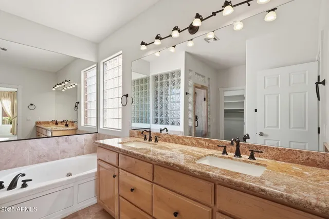 a bathroom with a granite countertop double vanity sink large mirror and a bathtub