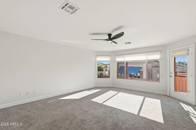 an empty room with windows and ceiling fan view