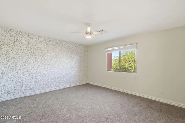 an empty room with a window and a ceiling fan
