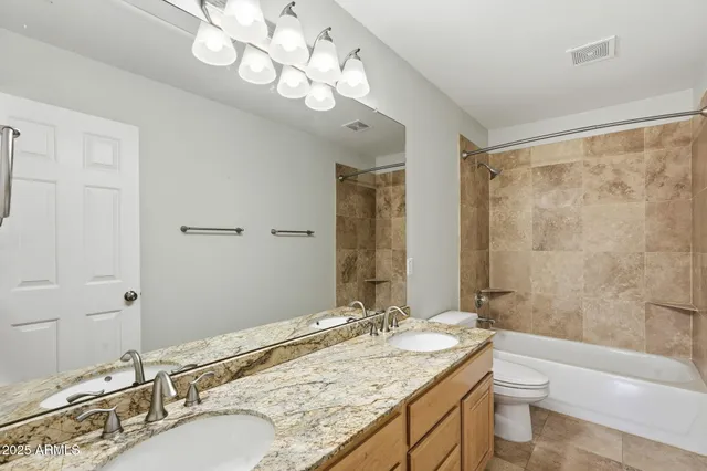 a bathroom with a granite countertop double vanity sink a toilet and shower
