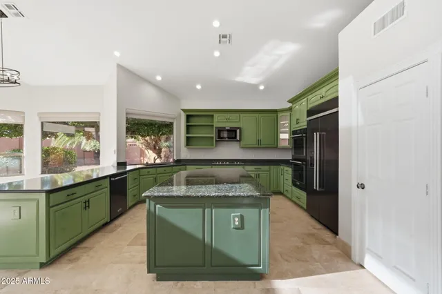 a kitchen with kitchen island granite countertop a sink and a refrigerator