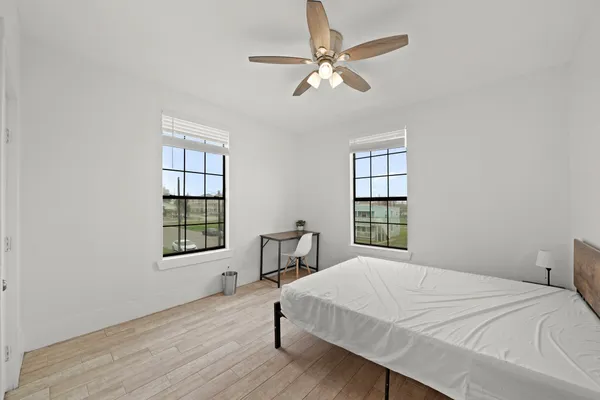 a bedroom with a bed windows and wooden floor