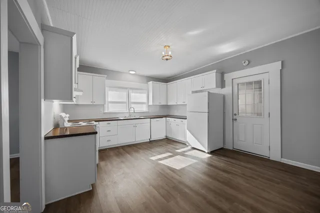 a kitchen with white cabinets and wooden floor