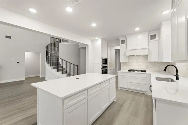 a kitchen that has a lot of white cabinets and stainless steel appliances