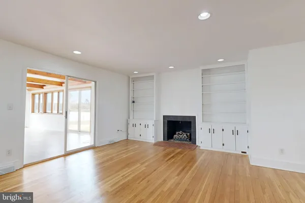 a view of empty room with wooden floor and fireplace