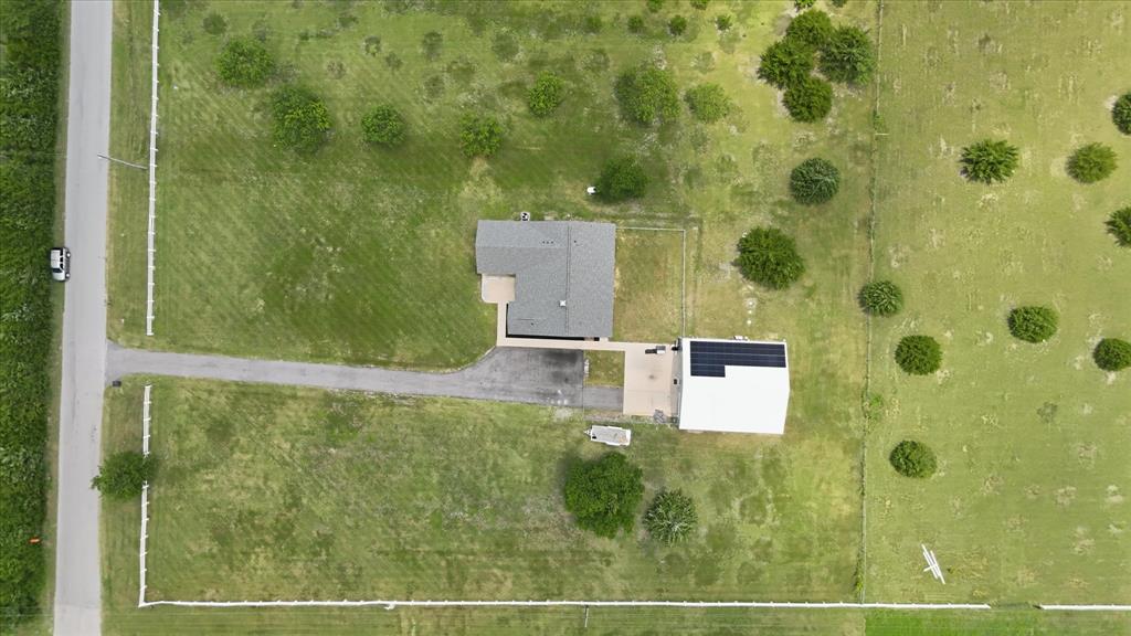 110 Highview Road Ennis, TX 75119 - Photo 38 of 40 Expansive property featuring a main residence with a gray shingle roof, a secondary structure with a white roof, solar panels, and a paved driveway